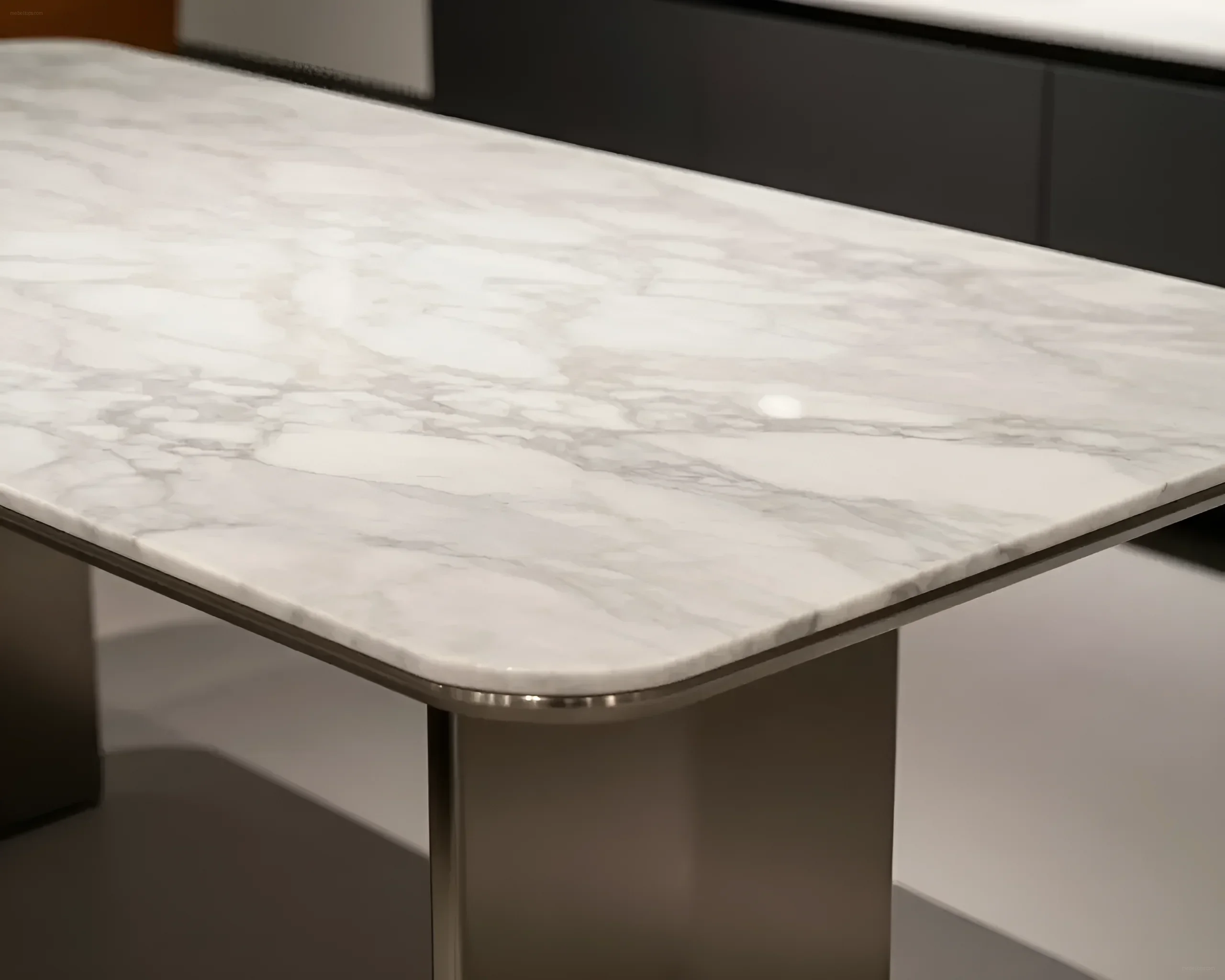 Close-up of a rounded white marble tabletop with gray veins, set on metal legs.