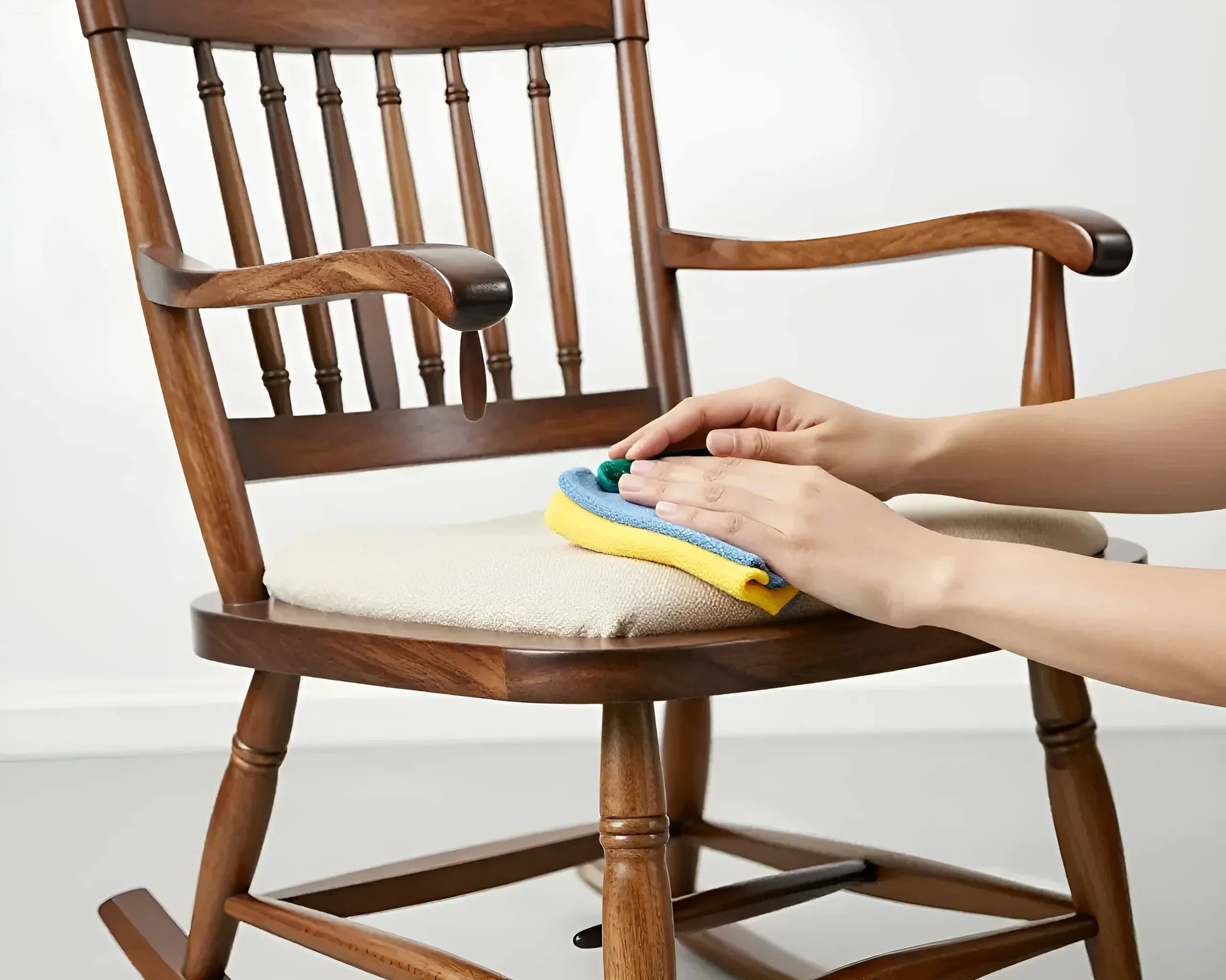 Hands wiping the cushion of a rocking chair with a soft cloth