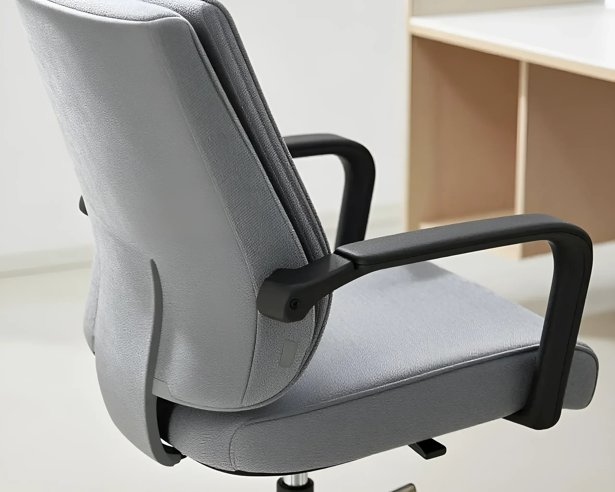 Ergonomischer Bürostuhl in Grau mit schwarzen Armlehnen, Seitenansicht, Fokus auf Rückenlehne und Sitzfläche.