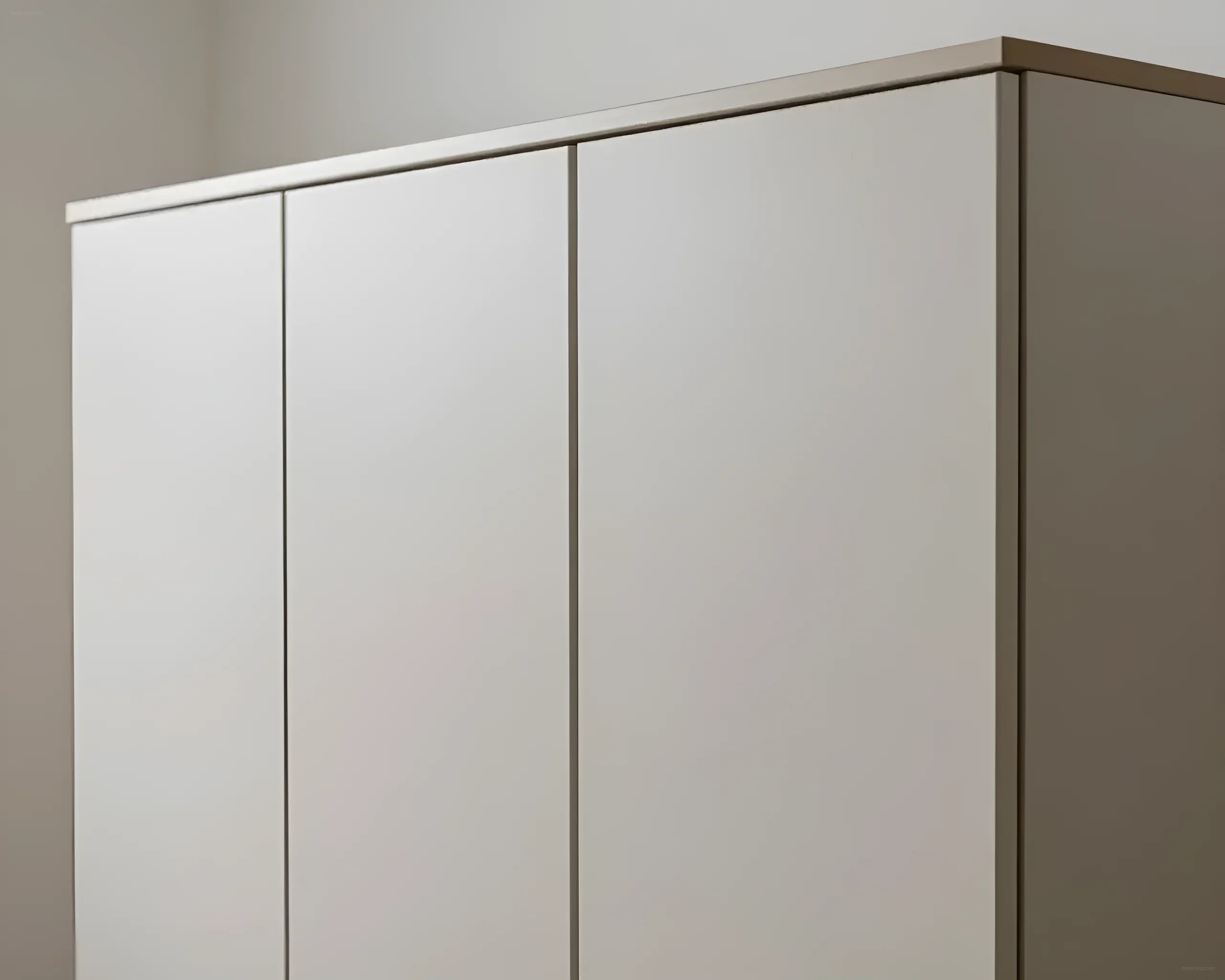 Nahaufnahme glatter Fronten eines modernen Schranks in neutralem Farbton, die mit der Wand verschmelzen.