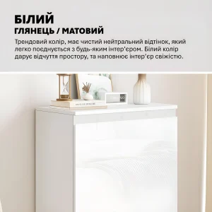 Белая глянцевая тумба модерн Флекс 600 мм с МДФ фасадами для игрушек, украшенная песочными часами, книгами и вазой на столешнице.