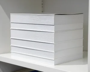 Стопка белых книг на белой полке, демонстрирующая чистоту и порядок.