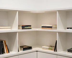 Белая угловая книжная полка с книгами и встроенной подсветкой