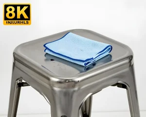 Блестящий металлический кухонный табурет с квадратным сиденьем и голубой салфеткой из микрофибры, готовой к уборке.